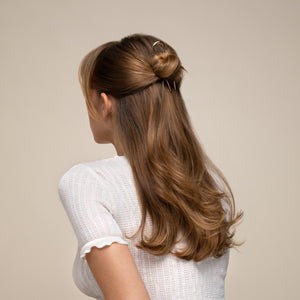 Woman with long brown hair styled in a half-up ponytail with the kitsch gold mini metal french hair pin against a beige background