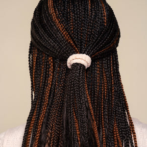 Black and brown hair styled with mirco braids with a white kitsch ribbed elastic hair tie on a neutral background