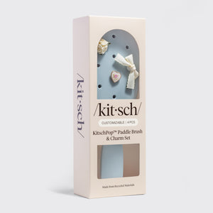 Kitsch paddle brush and charm set packaging on a light gray background