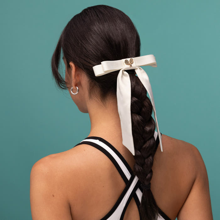 KITSCH Satin Bow Hair Clip - Cream — model styling the cream satin bow clip — secure all-day hold on all hair types — polished, put-together look