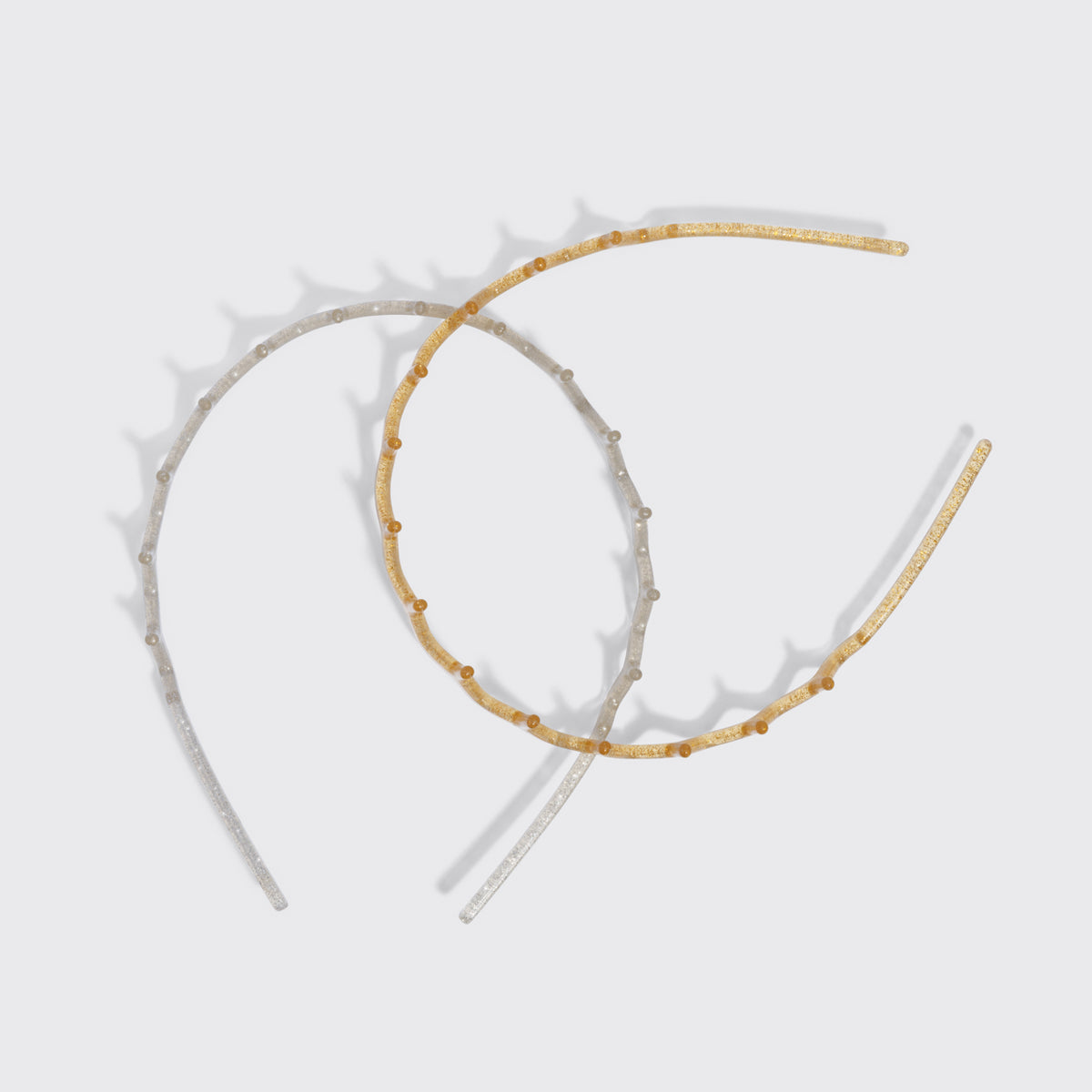 KITSCH Gold & Silver Zig Zag Headbands 2pc Set — the silver and gold zigzag headbands crossed on a grey background — Helps tame flyaways and loose strands — choosing between the two finishes