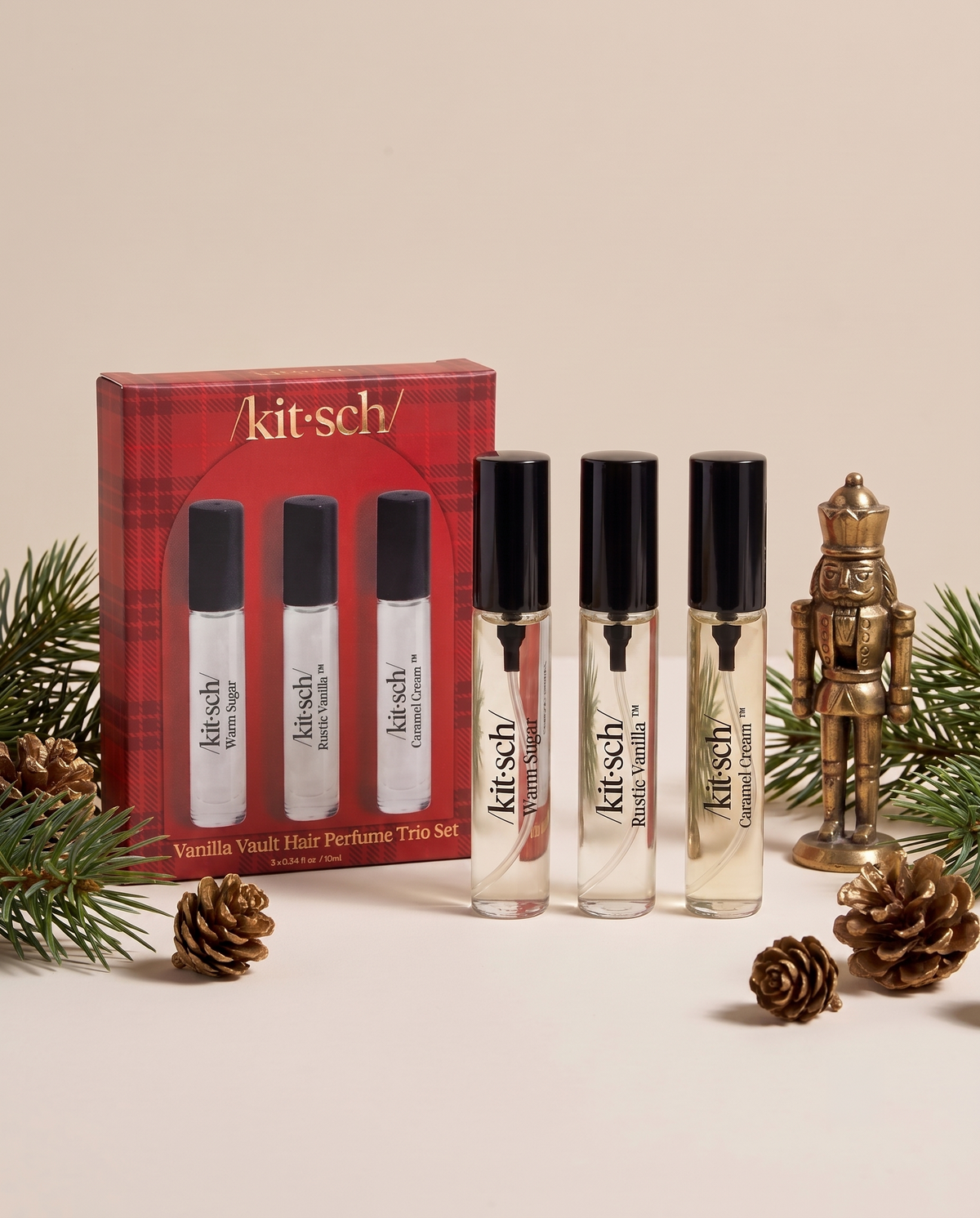 KITSCH Vanilla Vault Hair Perfume Trio Set — red plaid gift box with the three mini perfumes Warm Sugar, Rustic Vanilla and Caramel Cream beside a brass nutcracker, pinecones and pine branches on a cream backdrop — Patented technology helps neutralize unwanted odors at the source — a quick way to refresh your hair between washes